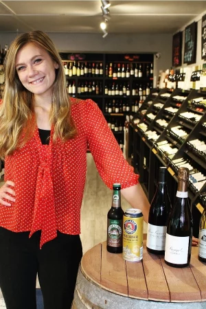 Coty standing next to a table displaying a number of beverages sold by The Blue Goat.